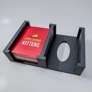 Exploding Kittens game box organizer insert. It is shown in black with the Exploding Kittens Game.