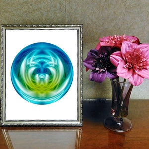 May include: A framed print of a colorful abstract design with a blue, green, and yellow orb in the center. The print is on a white background and is framed in a silver frame.