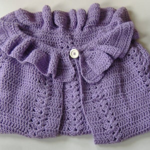 May include: A lavender crocheted shawl with a ruffled collar and a white button. The shawl has a delicate lace pattern and is finished with fringe.