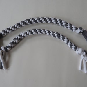 May include: Two gray and white braided dog toys. The toys are made from fabric and have frayed ends.