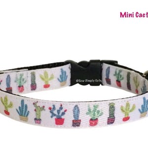 Może przedstawiać: Biały obroża dla psa z czarną klamrą i srebrnym kółkiem D. Obroża ma powtarzający się wzór kolorowych kaktusów w doniczkach. Na klamrze nadrukowany jest tekst "Sew Pimpily Cute".