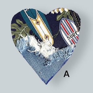 May include: Heart-shaped fabric patch with a denim base and a patterned top featuring surfboards and tropical leaves. The patch has frayed edges and the word "SURF" is visible. The letter "A" is in the bottom right corner.
