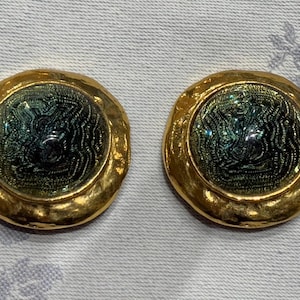 May include: A pair of gold-tone earrings with a green and blue swirl design.