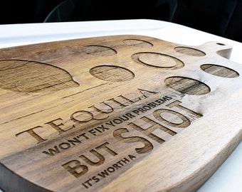 Könnte beinhalten: Holztablett mit sechs runden Aussparungen für Schnapsgläser. Das Tablett trägt die Gravur "Tequila won't fix your problems but it's worth a shot".