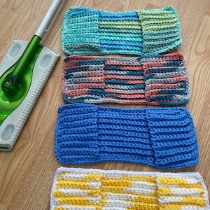 Puede incluir: Cuatro paños de cocina de ganchillo en diferentes colores y patrones. Los paños de cocina están hechos con una variedad de puntadas y colores, incluyendo azul, verde, amarillo, blanco y rosa. Los paños de cocina están dispuestos sobre una superficie de madera.