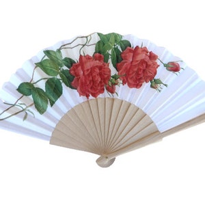 May include: A white folding fan with a wooden handle and a floral design featuring red roses and green leaves.