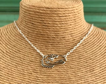 May include: A silver chain necklace with a silver pendant shaped like a bird's head. The pendant has a small clear stone in the center.