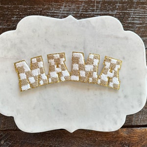 May include: The word "MAMA" spelled out in gold letters with a white and brown checkered pattern.