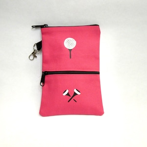 May include: A pink zippered pouch with a golf ball and tee design. The pouch has two compartments and a black zipper pull.