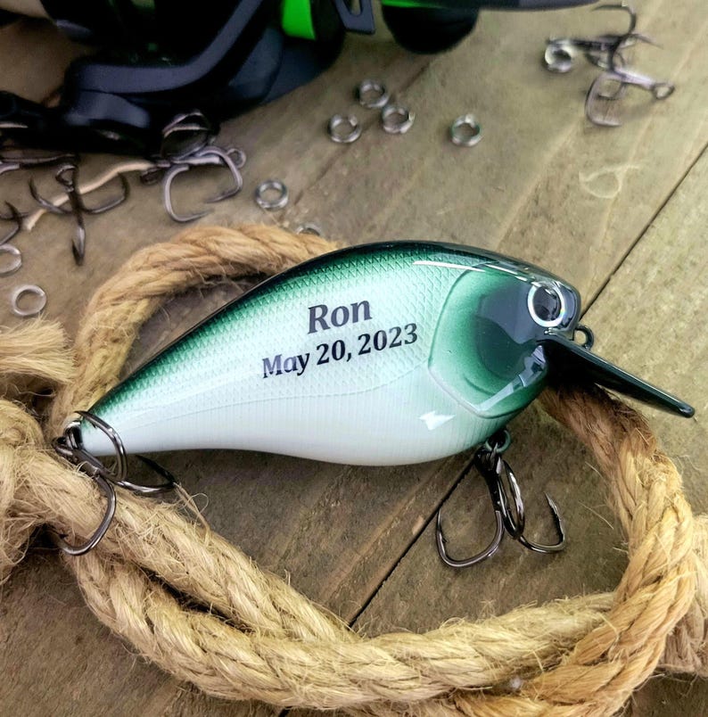 A personalized fishing lures with the name "Ron" and the date "May 20, 2023" printed on it, along with a green and white color scheme.