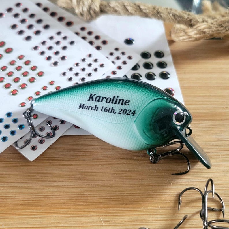 A personalized fishing lure with the name "Karoline" and the date "March 16th, 2024" printed on it, along with a green and white color scheme.