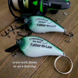 two green and white fishing lures with the text "I Hooked the best Father-in-Law" printed on them, along with a keyring.