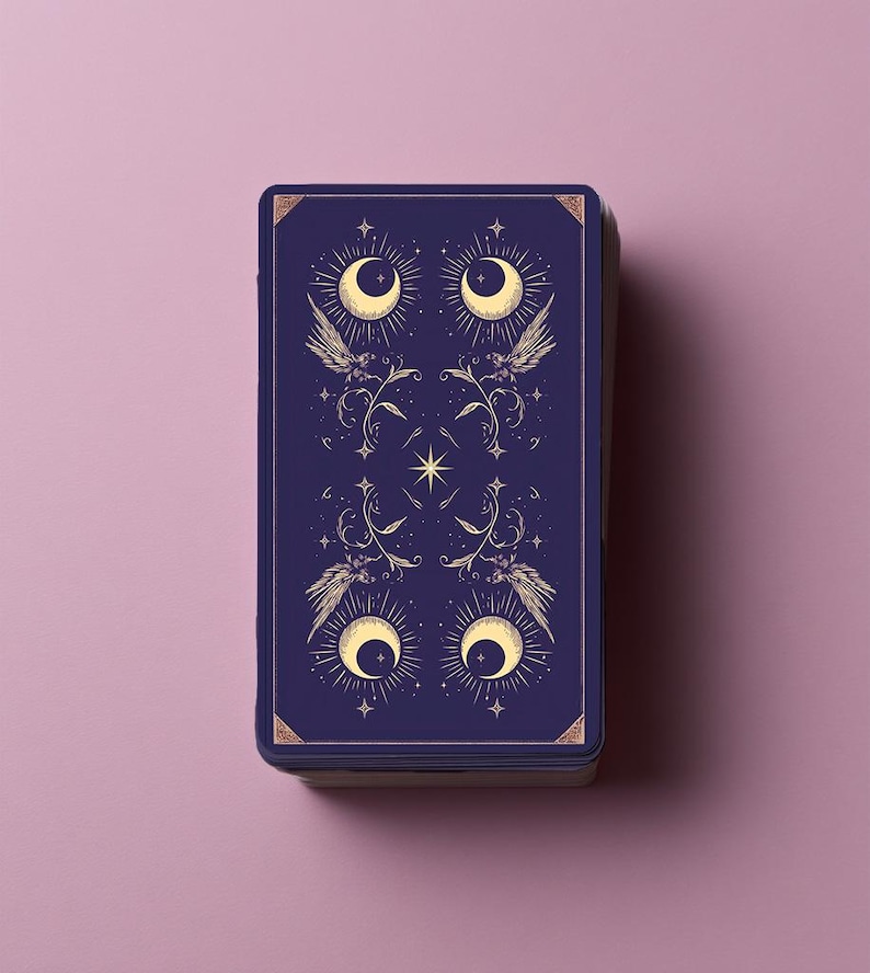 Puede incluir: Una baraja de cartas de tarot rectangular con un dise&ntilde;o de reverso en azul marino profundo, con ilustraciones en color dorado de cuatro lunas crecientes, alas estilizadas, enredaderas florales y peque&ntilde;as estrellas en un patr&oacute;n sim&eacute;trico.