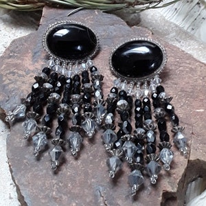 May include: A pair of black and silver dangle earrings with black oval-shaped stones and crystal beads.