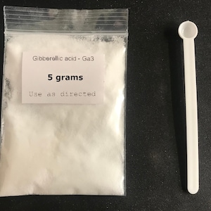 May include: A clear plastic bag containing a white powder, labeled "Gibberellic acid - Ga3" with "5 grams" and "Use as directed" printed on a white label. A white plastic scoop is next to the bag.