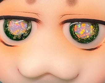 May include: Close-up of a doll's face with striking features. The eyes are the focal point, featuring vibrant green irises with a shimmering, multi-colored effect. Eyelashes are delicately drawn, and the skin has a soft, peach tone.