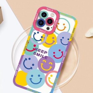 May include: A white phone case with a colorful design featuring smiley faces and the text "Keep Smile" and "Good Luck".