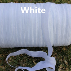 May include: A spool of white elastic ribbon, with the word "White" printed on the spool.