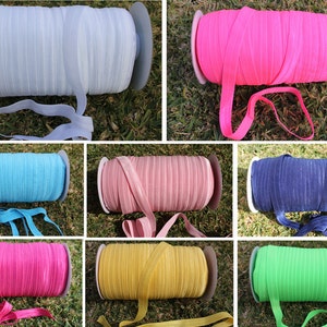 May include: A collection of 10 spools of colourful elastic ribbon. The colours include light blue, pink, blue, navy, hot pink, yellow, and green.