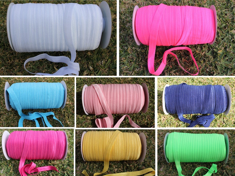 May include: A collection of 10 spools of colorful elastic ribbon. The colors include light blue, pink, blue, navy, hot pink, yellow, and green.