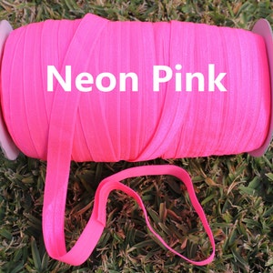 May include: A spool of neon pink elastic ribbon. The ribbon is wound around a cardboard spool with a white label that says "Neon Pink".