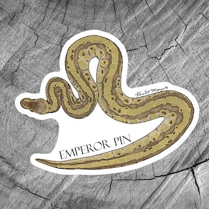 May include: A sticker featuring a detailed illustration of a yellow and brown Emperor Pin snake, with the text "EMPEROR PIN" below the snake.