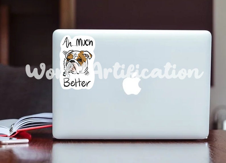 May include: A white laptop with a sticker of a bulldog with the text "Ah...Much Better" on it.
