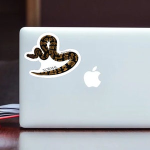May include: A sticker of a brown and black snake with the word "NORMAL" printed below it.