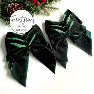 May include: Two forest green velvet bows with long, flowing tails and a central knot. A circular white label is positioned above the bows with the text Forest green All sizes and styles written in black script and sans-serif font.