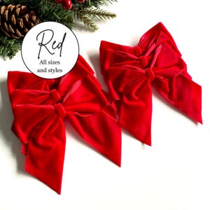 May include: Two bright red velvet bows with long, flowing tails and a central knot. A circular white label is positioned above the bows, featuring the black text "Red" followed by "All sizes and styles" in a smaller font.