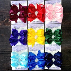 May include: Nine sets of hair bows in various colours, including burgundy, red, pink, purple, yellow, green, light blue, royal blue, and navy. Each set features two bows on a card with the text "Honeybowbow Accessories".