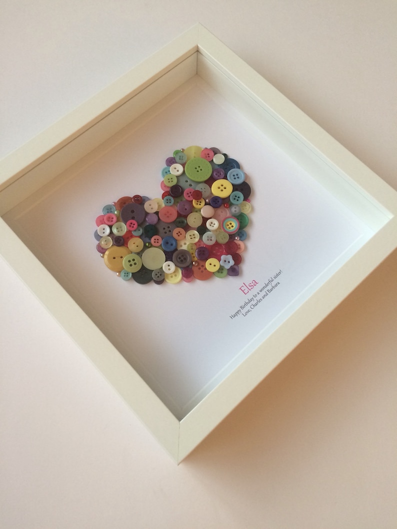 May include: A framed heart made of colorful buttons with the name "Elsa" and the message "Happy Birthday to a wonderful sister! Love, Charles and Barbara" written below.