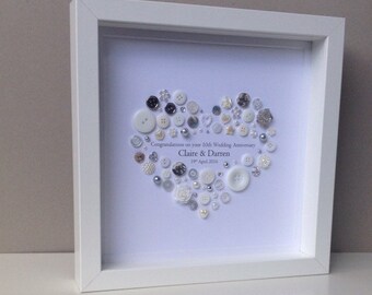 May include: A white framed picture with a white background and a heart made of white and silver buttons. The text "Congratulations on your 10th Wedding Anniversary Claire & Darren 19th April 2016" is written below the heart.