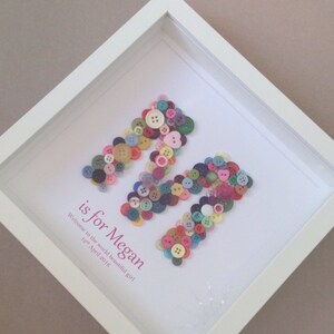 May include: A white frame with a white background and a letter M made of colorful buttons. The text "is for Megan" is written below the letter M. The text "Welcome to the world beautiful girl 12th April 2015" is written below the text "is for Megan".