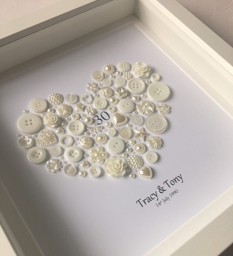 May include: A white framed heart-shaped artwork made of white buttons, pearls, and other embellishments. The number 30 is in the center of the heart. The text below the heart reads "Tracy & Tony 14th July 1990".