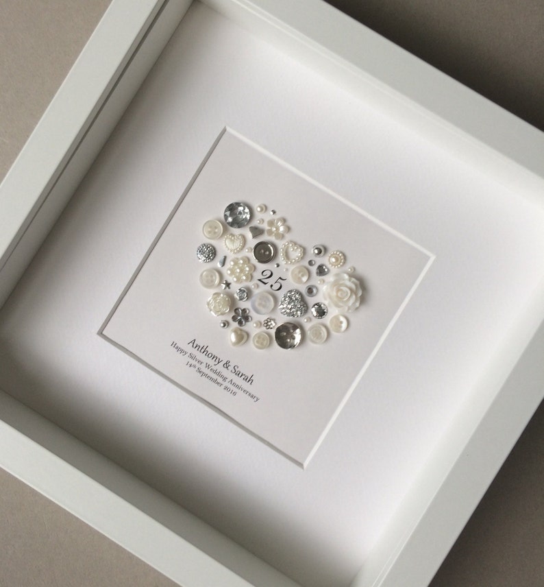 a handmade silver anniversary frame with silver and pearl buttons and embellishments in a heart shape is the good gift for 25th wedding anniversary gift