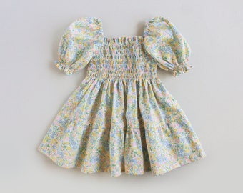 Puede incluir: Un vestido de estampado floral azul claro y amarillo con mangas abullonadas y un corpiño fruncido.