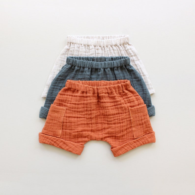 May include: Three pairs of cotton shorts in different colors: orange, gray, and white. The shorts have a relaxed fit and are made of a soft, breathable fabric.