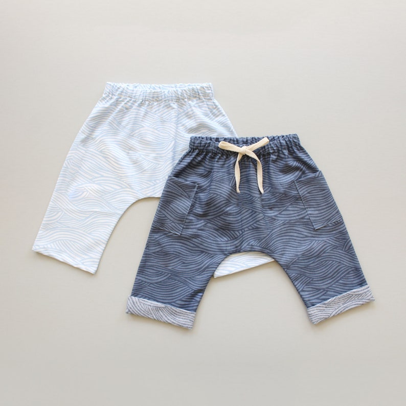 May include: Two pairs of baby pants with a wave pattern. One pair is light blue and the other is dark blue.