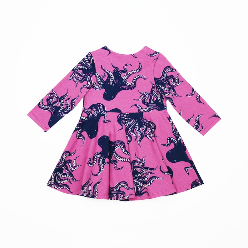 May include: A pink long-sleeved dress with a navy blue octopus print. The dress has a flared skirt and a round neckline.