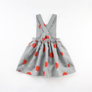 May include: A gray and red polka dot dress with adjustable straps. The straps cross in the back.