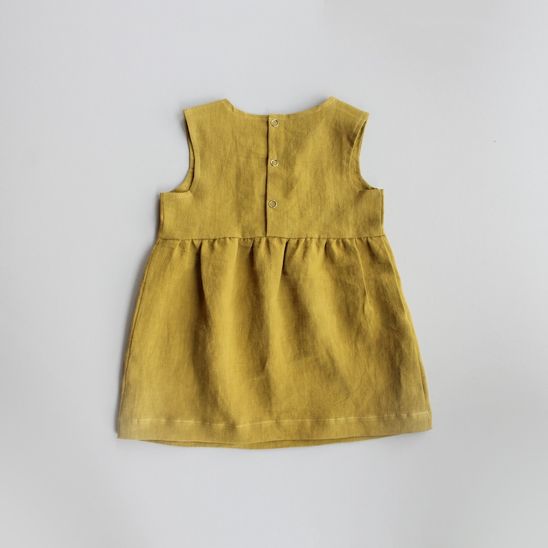 May include: A sleeveless, yellow linen dress with a gathered skirt and button closure in the back.