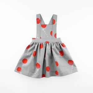 May include: A gray and red polka dot dress with straps. The dress has a gathered skirt and white bird designs.