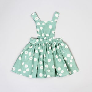 May include: A green and white polka dot dress with straps. The dress has a gathered skirt and a simple bodice.