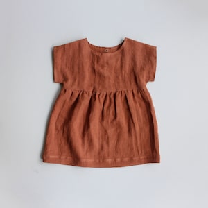 May include: A rust-colored linen dress with short sleeves and a gathered skirt.