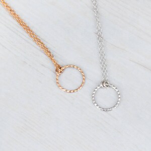 Puede incluir: Dos delicados collares con eslabones de cadena retorcidos y un simple colgante circular. Un collar es dorado y el otro es plateado.