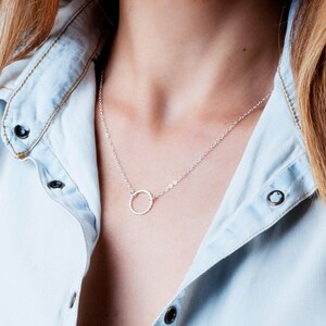 Puede incluir: Un collar de plata con un colgante circular texturizado.