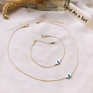 May include: A set of two gold chain necklaces, each featuring a blue evil eye charm. The necklaces are layered and the charms are of different sizes. The text "Sold As a Set" is visible in the image.