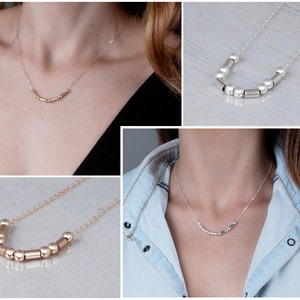 Puede incluir: Tres collares con una cadena delicada y una fila de peque&ntilde;as cuentas doradas y plateadas. Las cuentas son una mezcla de formas redondas y cil&iacute;ndricas.