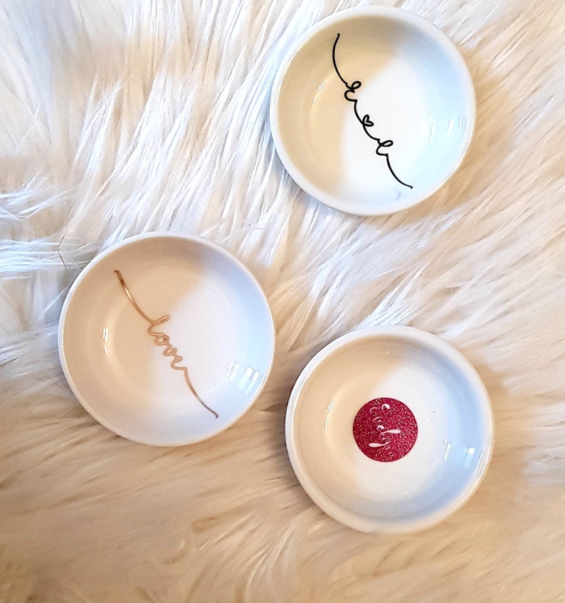 May include: Three small white ceramic dishes with gold and black lettering. The dishes say "love", "sweet", and "pretty".